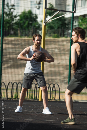 Man holding basketball ball near blurred friend on playground