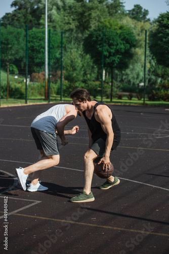 Young man playing streetball with friend on outdoor playground