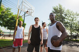 Young interracial men with basketball ball looking at camera on playground outdoors