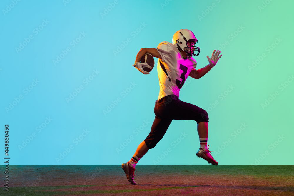 Portrait of American football player training isolated on blue studio background in neon light. Concept of sport, competition