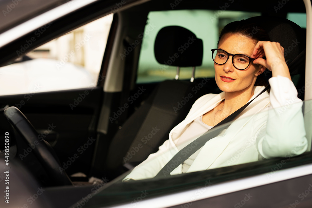 Beautiful businesswoman driving a car. Portrait of smiling woman sitting in the car.