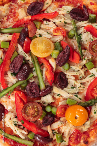 Fresh baked pizza with olives, tomato, and chicken.