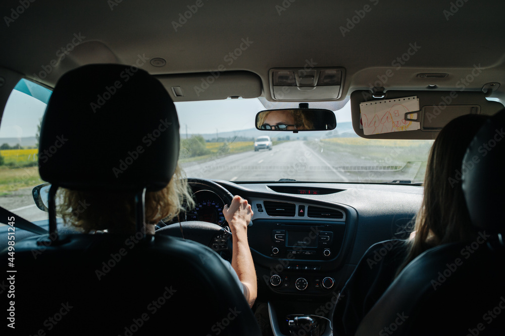 Woman driving her car through a countryside. Backseat view