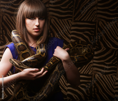 Young brunette woman holding python, big snake.