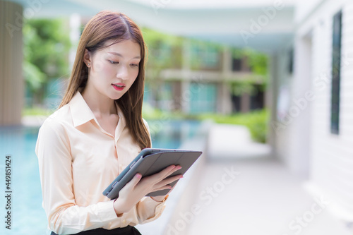 Asian professional working young woman uses tablet to search data in working from anywhere concept.