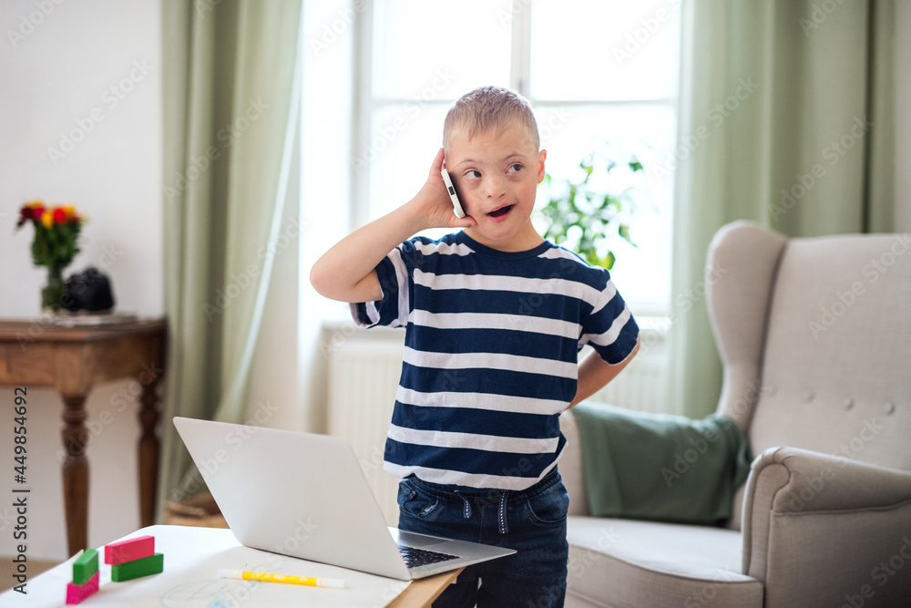 Happy down syndrome son indoors at home, using smartphone. Happy down syndrome son indoors at home, using smartphone.