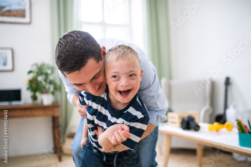 Slika na platnu Father with happy down syndrome son indoors at home, having fun.