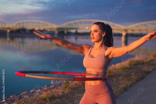 Young woman doing hula hoop exercise at riverside photo