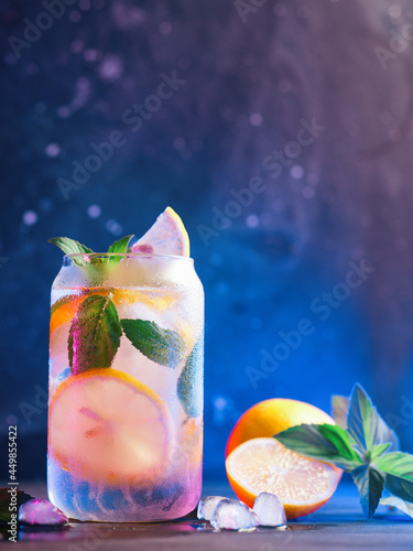 Refreshing cold tonic with lemon and mint, ice lemonade in a glass, neon stylish background photo