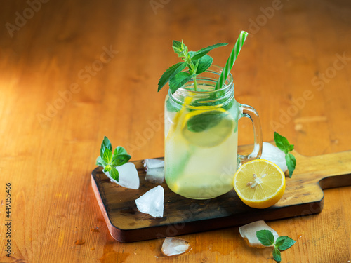 Summer refreshing detox water with lemon and mint, refreshing mojito in a jar on a wooden table