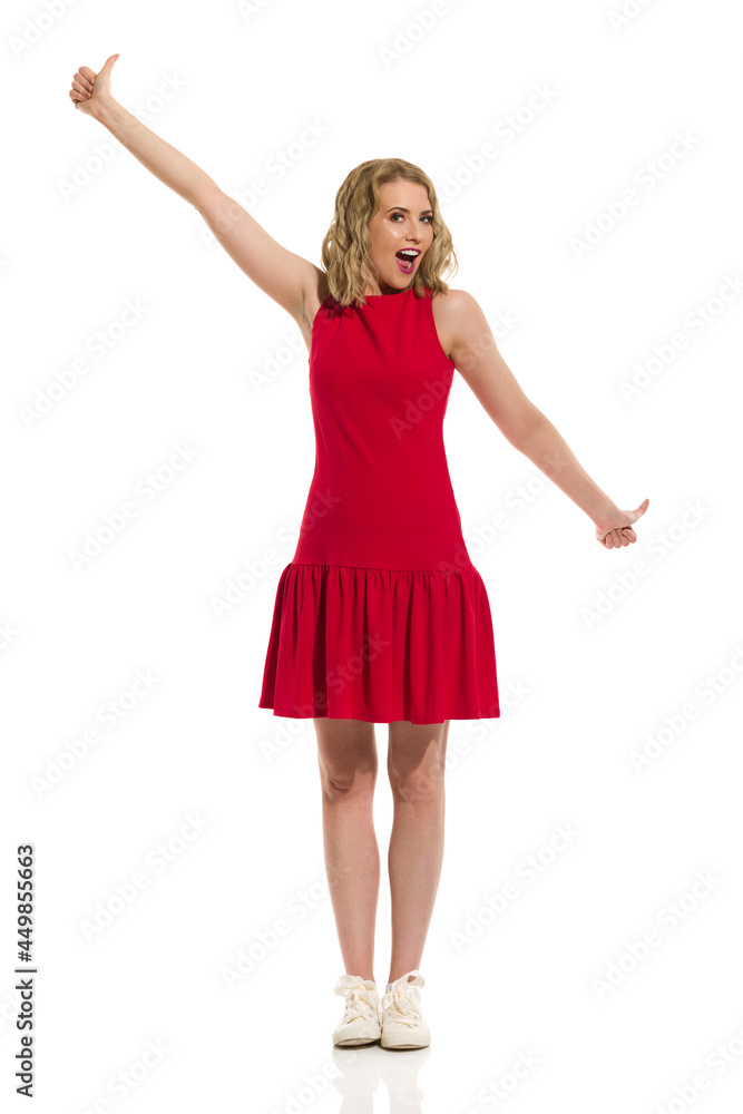 Happy Young Woman In Red Mini Dress And Sneakers Is Showing Thumbs Up And Shouting. Happy Young Woman In Red Mini Dress And Sneakers Is Showing Thumbs Up And Shouting.