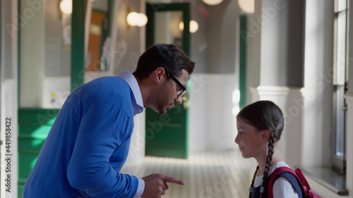 Foto Side view of indian male teacher reprimanding preteen schoolgirl in corridor