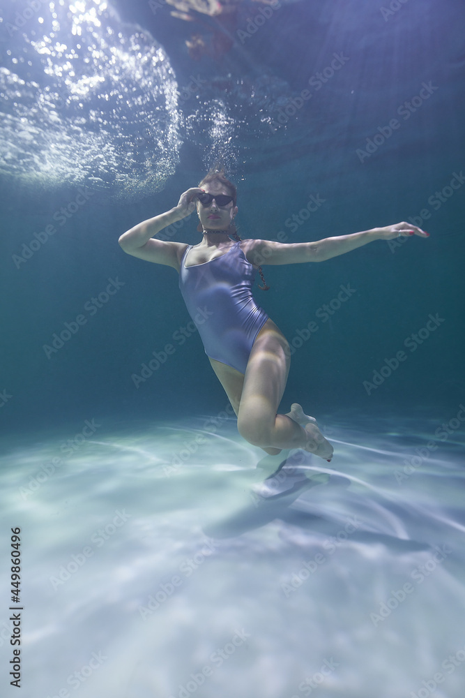 fashion model posing underwater in the pool in a silver swimsuit and sunglasses fashion model posing underwater in the pool in a silver swimsuit and sunglasses