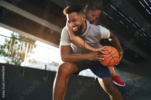 Man and woman friends playing basketball outdoors in city, having fun.