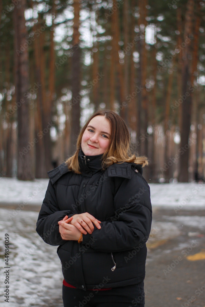 happy girl in the park in a black jacket in winter happy girl in the park in a black jacket in winter