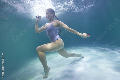 freediver girl dives underwater in the pool in a silver swimsuit and sunglasses © Pavel Karchevskii