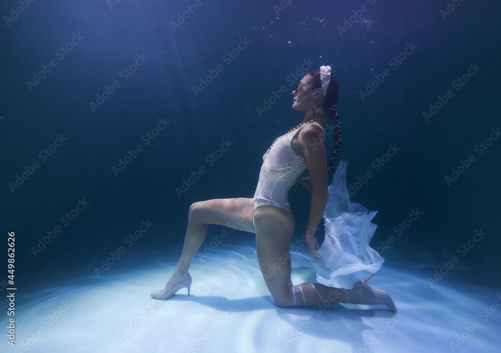 Fototapeta premium girl in a headdress at the bottom of the pool in the sun