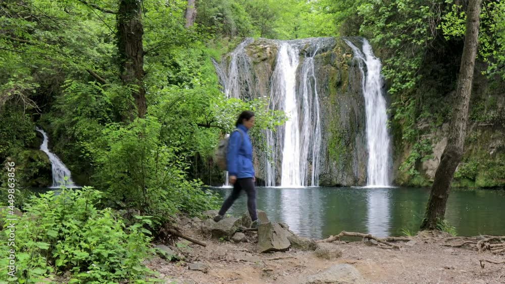 Tourist woman walking near beautiful waterfall in Spain, near from village Rupit in Catalonia Tourist woman walking near beautiful waterfall in Spain, near from village Rupit in Catalonia