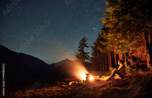 Papier peint Side view of silhouette of woman having a rest near forest in campsite