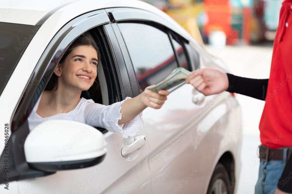 driver or customer paying in cash to worker after refueling a vehicle at gas station driver or customer paying in cash to worker after refueling a vehicle at gas station