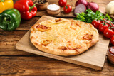 Delicious khachapuri with cheese and vegetables on wooden table