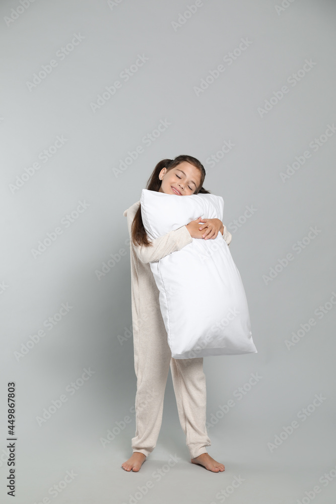 Cute girl in white pajamas hugging pillow on light grey background Cute girl in white pajamas hugging pillow on light grey background