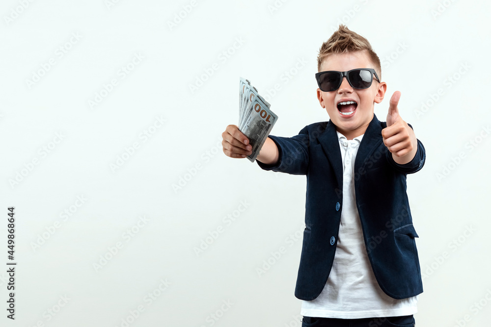 A rich boy in glasses holds dollars against the background of falling banknotes. knows how to make money. Money rain, Financial education, young millionaire, investments, loans, winnings. A rich boy in glasses holds dollars against the background of falling banknotes. knows how to make money. Money rain, Financial education, young millionaire, investments, loans, winnings.