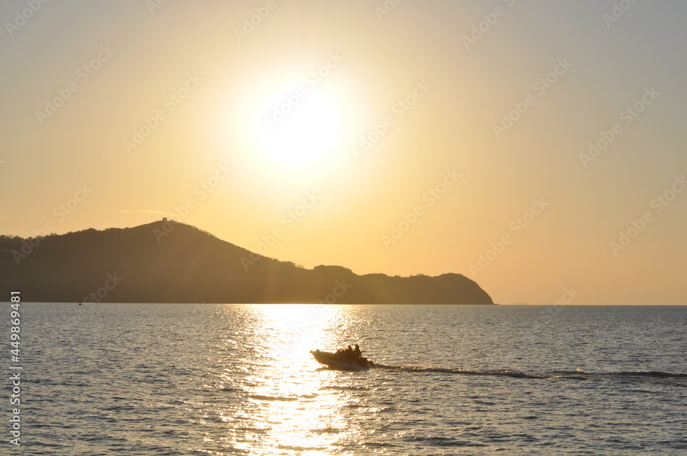 Small boat traveling at high speed on the sea at sunset going across the sun reflection on the water