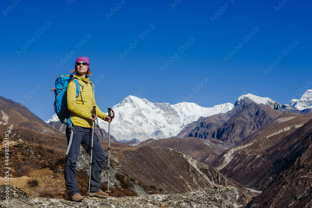 Woman Traveler with Backpack hiking in Mountains with beautiful summer Himalayas landscape on background