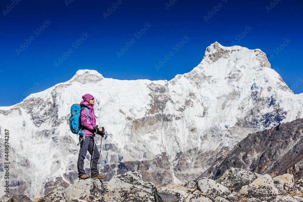 Woman Traveler with Backpack hiking in Mountains with beautiful Himalaya landscape on background. Mountaineering sport lifestyle concept