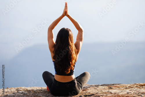 Young woman is practicing yoga at mountain in the summer