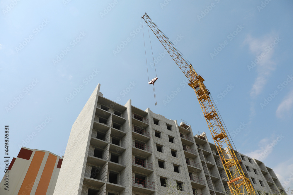 Fototapeta premium Unfinished building and construction crane outdoors, low angle view