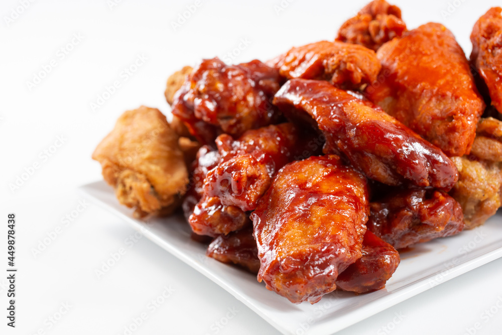 A view of a plate of a chicken wings sampler, featuring flavors as BBQ sauce and buffalo style.