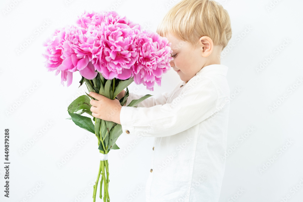 child blonde boy with big bouquet of pink peonies on white background. Love and romantic concept