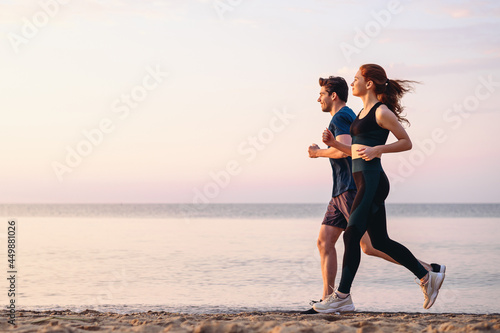 Full body profile couple young two friends strong sporty sportswoman sportsman woman man 20s in sport clothes warm up training run on sand sea ocean beach outdoor jog on seaside in summer day morning. photo