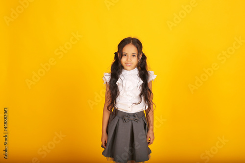 a beautiful happy dark-skinned schoolgirl girl with dark hair in a school uniform, a gray skirt and a white blouse