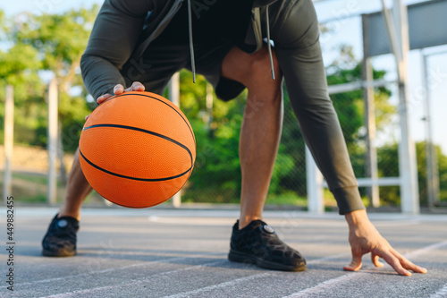 Cropped close up young sporty strong caucasian sportsman man 20s wear grey dark sportswear clothes dribbling training with ball at basketball game playground court. Outdoor courtyard sports concept