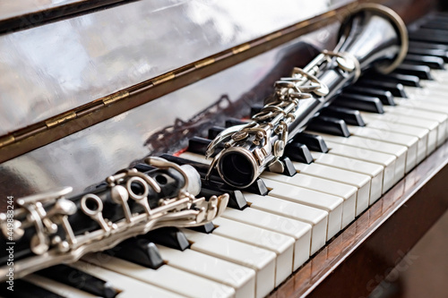 Canvas Print The clarinet, disassembled in half, lies on the piano by the sunny window
