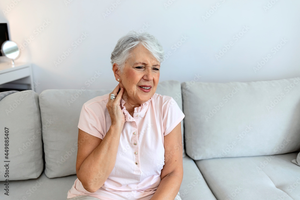 Shot of a senior woman experiencing neck pain at home. Neck and shoulder pain, old woman suffering from neck and shoulder injury, health problem concept. Pretty elderly lady touching her aching neck. Shot of a senior woman experiencing neck pain at home. Neck and shoulder pain, old woman suffering from neck and shoulder injury, health problem concept. Pretty elderly lady touching her aching neck.