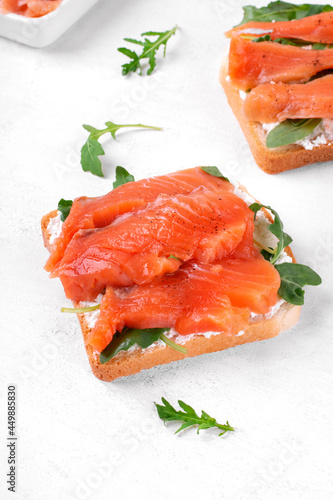 Toast with salted trout, cream cheese and arugula on the white table photo