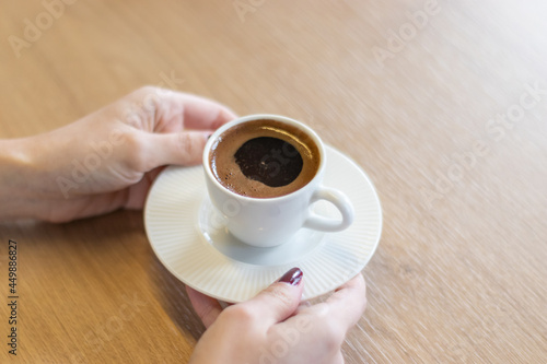 The woman on the wooden table holding Turkish coffee with your hands