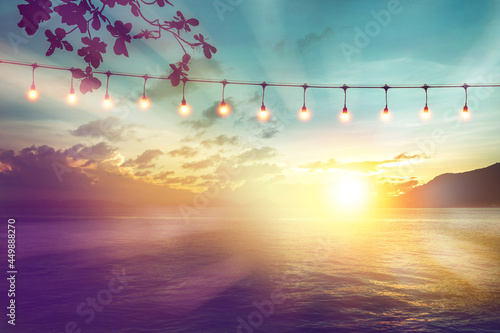Canvas Print blurred bokeh light on sunset with yellow string lights decor in beach restauran