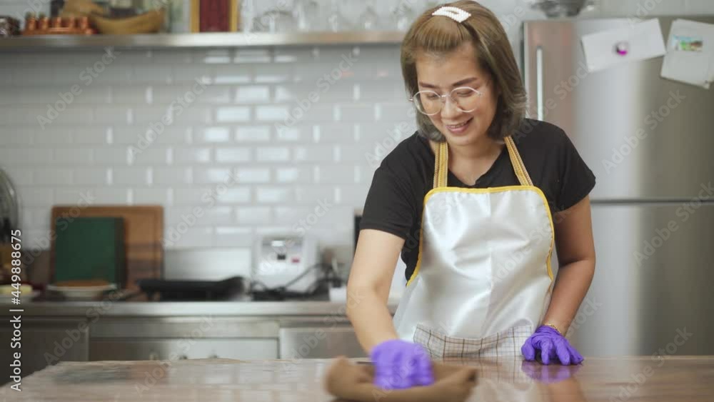 Smiling beautiful asian women wearing rubber gloves, involved in wiping kitchen surfaces at home, keeping house neat. Happy female cleaning worker mopping dust indoors. Smiling beautiful asian women wearing rubber gloves, involved in wiping kitchen surfaces at home, keeping house neat. Happy female cleaning worker mopping dust indoors.