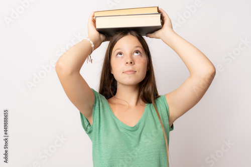 Portrait of a cheerful pretty girl holding books and looking above isolated over white background