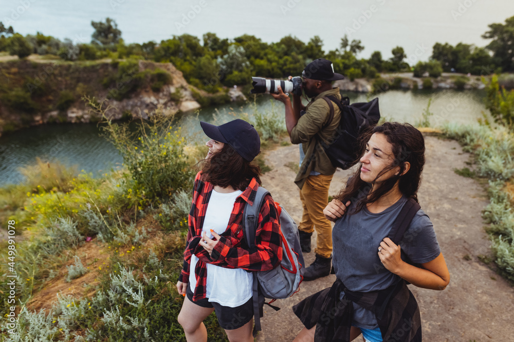 Group of friends, young men and women walking, strolling together outskirts of city, in summer forest, meadow. Active lifestyle, friendship, care, ecology concept