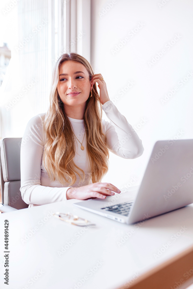 Blond young woman working on her laptop at the office Blond young woman working on her laptop at the office