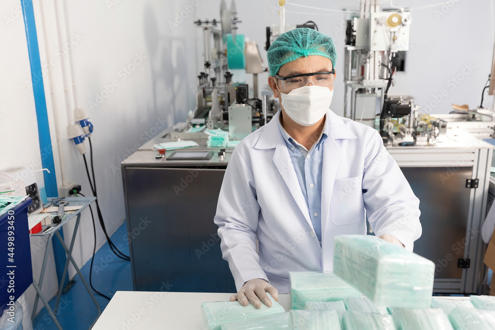 male factory worker holding packaging a lot of medical face masks and checking of quality from machine male factory worker holding packaging a lot of medical face masks and checking of quality from machine