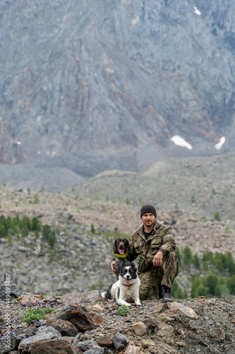 Hunter with two dogs sitting against the background of a mountain