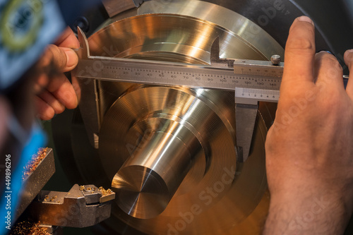 The machine operator use Vernier caliper measure brass material parts . photo