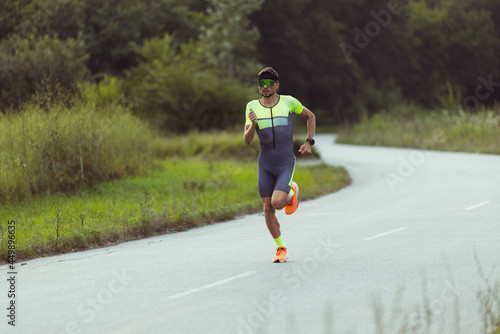 Fotografie Young professional male triathlete, runner in motion on open road